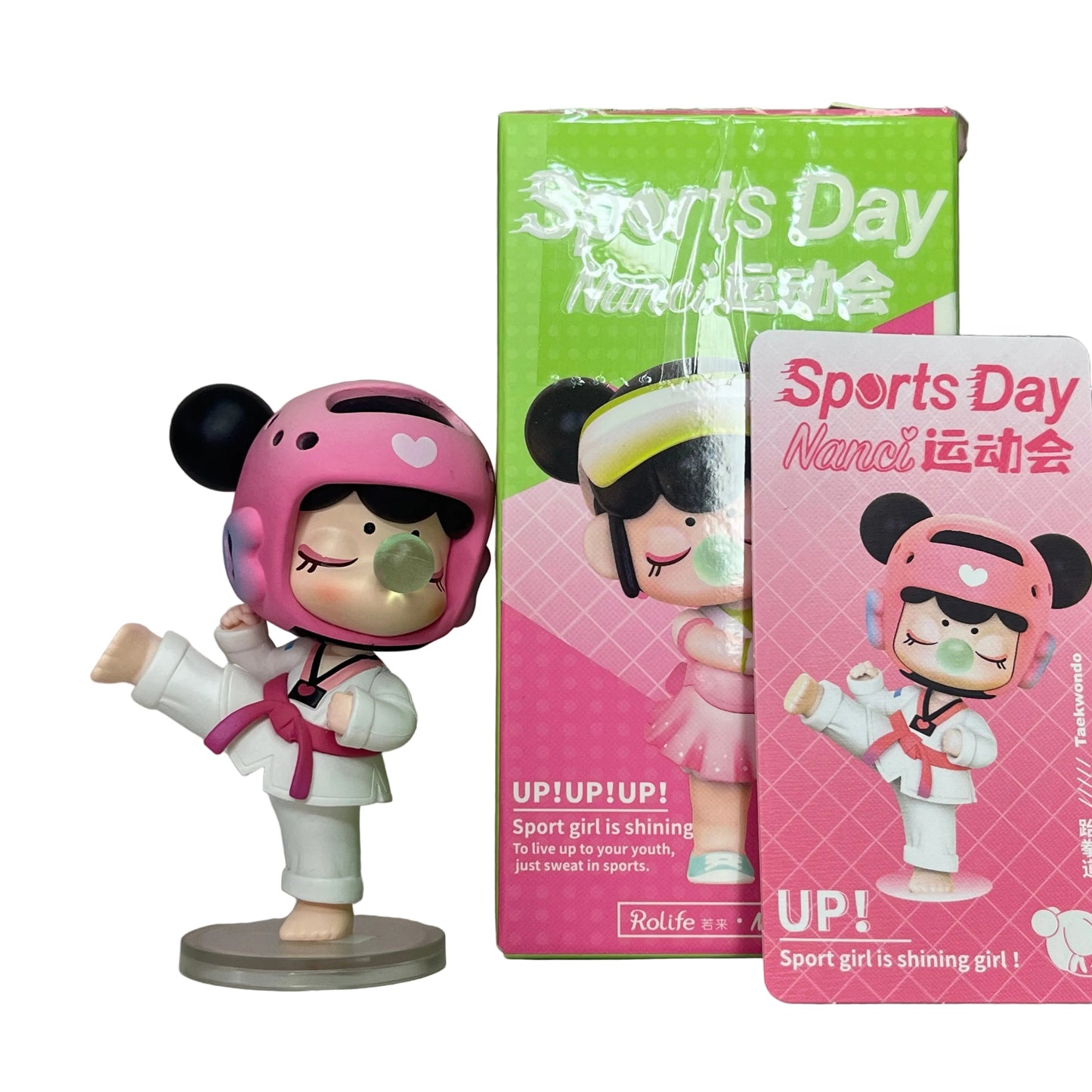 Figurine of a girl in athletic gear with pink helmet and packaging for 'Sports Day Nanci' on a light background